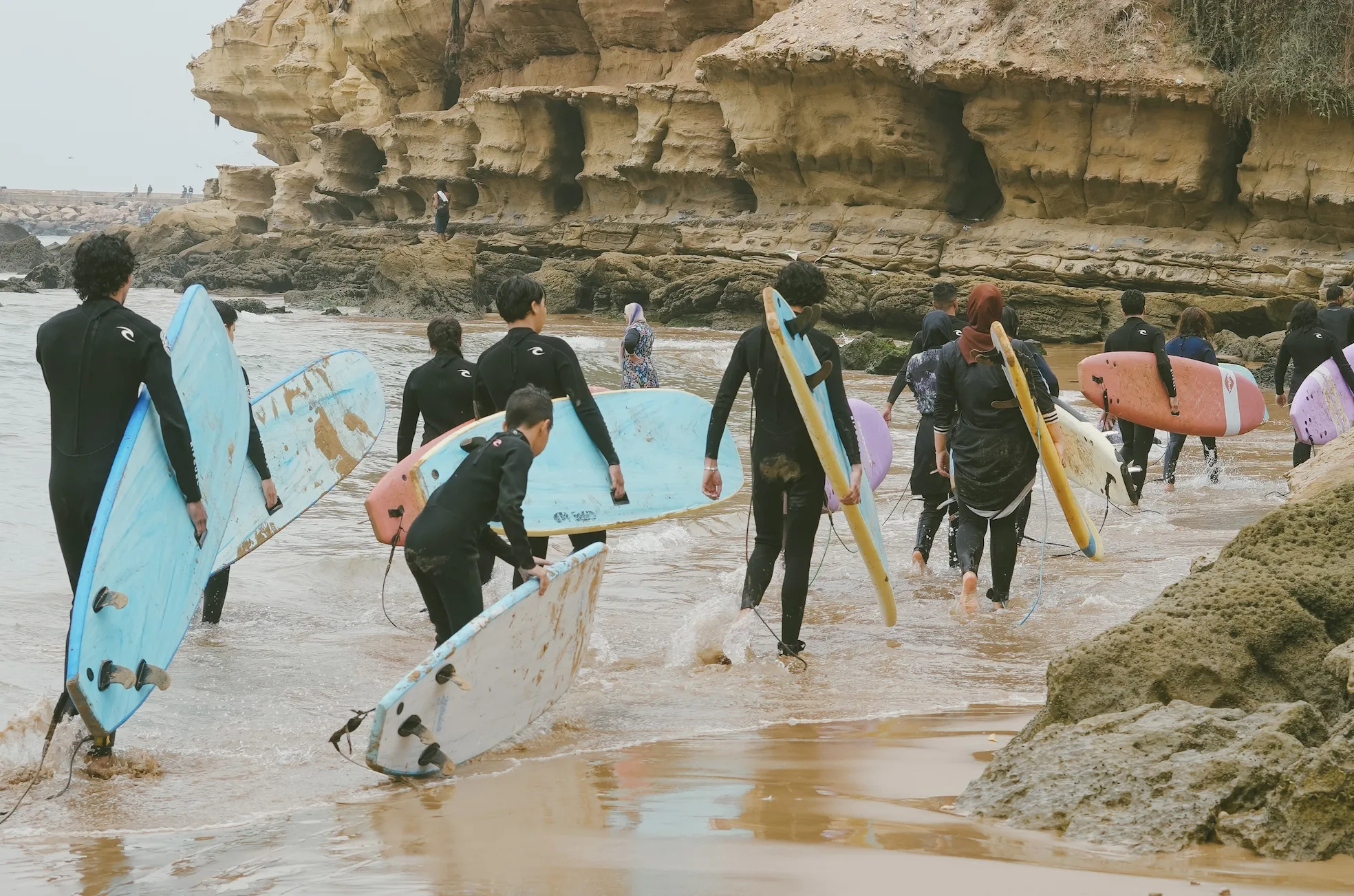 Surfers in wetsuits riding waves in the bay of Imsouane, Morocco